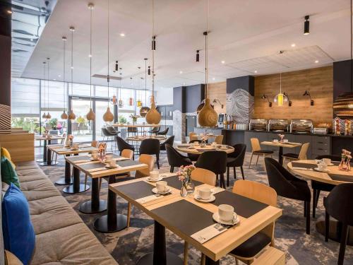 a restaurant with tables and chairs and a kitchen at Novotel Szczecin Centrum in Szczecin