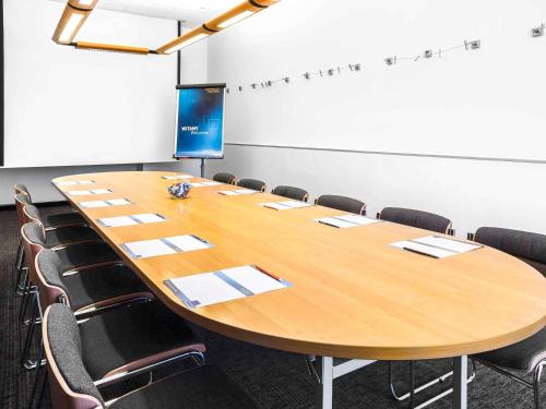 a conference room with a large wooden table and chairs at Novotel Szczecin Centrum in Szczecin