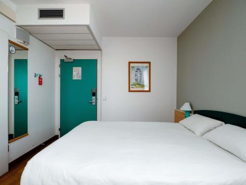 a bedroom with a white bed and a green door at Ibis Częstochowa in Częstochowa
