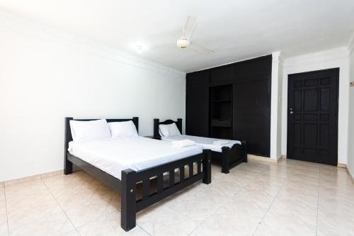 a bedroom with two beds and a black door at Hotel Costa Caribe BAQ in Barranquilla