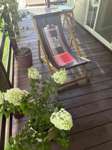 a rocking chair on a deck with a table and flowers at Korzkiewka 
