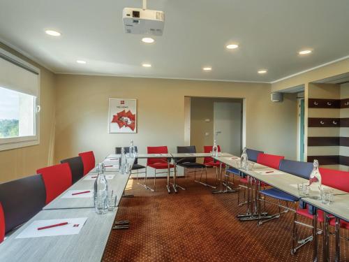 a conference room with long tables and red chairs at Ibis Częstochowa in Częstochowa