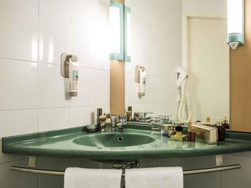 a bathroom with a green sink and a mirror at Ibis Szczecin Centrum in Szczecin