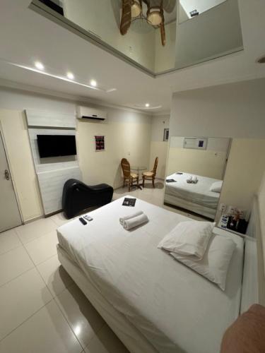 a bedroom with a large white bed and a table at D'lazer Motel in Caruaru