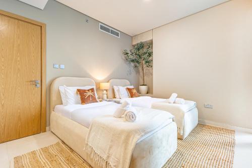 two beds in a room with white walls at Groups and Families Paradise - 5 min from ADGM, Galleria, Cleveland, Beach, etc - Designer's Choice - New Building - Heart of Al Reem in Abu Dhabi