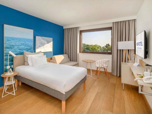 a hotel room with a large bed and a desk at Novotel Gdańsk Marina in Gdańsk