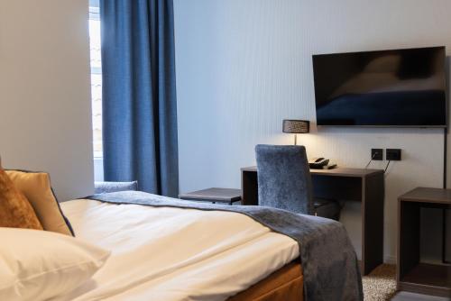 a hotel room with a bed and a desk and a tv at Quality Hotel Florø in Florø