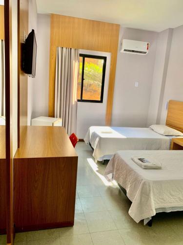 a hotel room with two beds and a television at Hotel Rinkao in Cachoeiro de Itapemirim