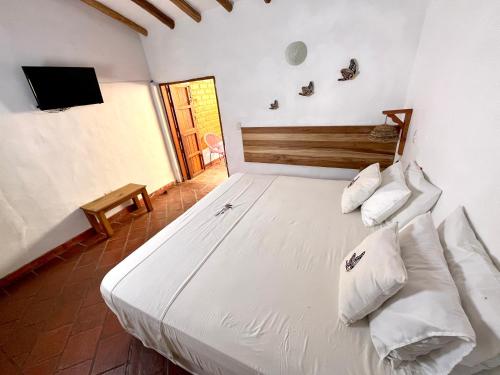a bedroom with a large white bed with pillows at Hotel Victoria Barichara in Barichara