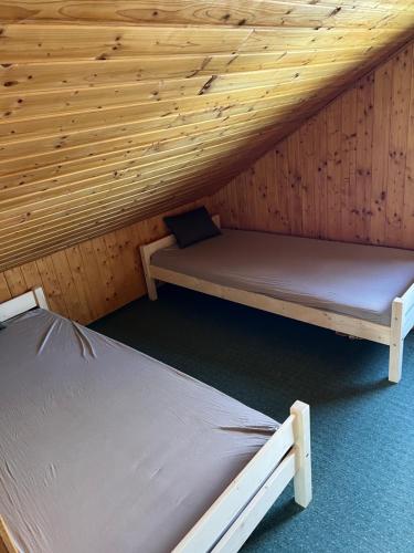 two beds in a cabin with a wooden ceiling at Bokodi üdülő és horgászházak in Oroszlány