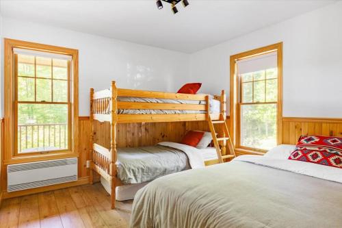 a bedroom with two bunk beds and two windows at Le Chalet Orange in Shawinigan