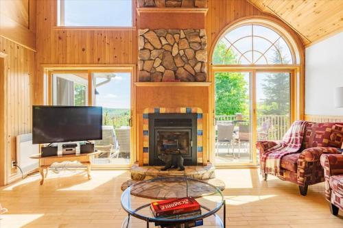 a living room with a fireplace and a tv at Le Chalet Orange in Shawinigan