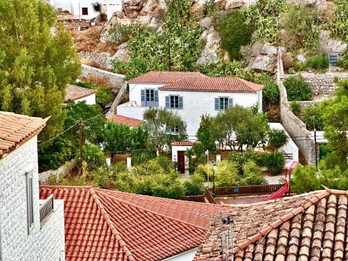 a white house with red tile roofs in a village at Kaminēa in Hydra