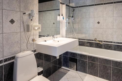 a bathroom with a white sink and a toilet at Quality Hotel Florø in Florø