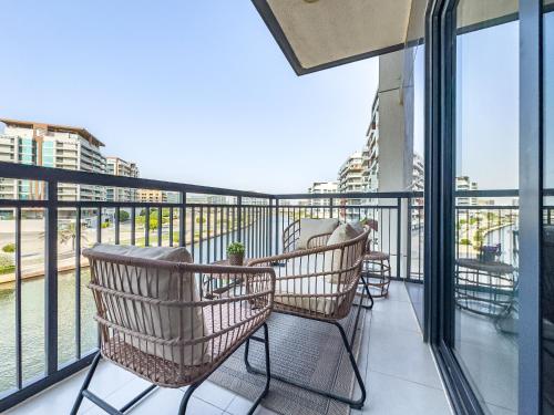 a balcony with chairs and a view of a city at Amazing Rooftop Pool - Full Canal Views - 1 BDR - 5 min walk from Space42 Arena - Heart of Raha Beach in Abu Dhabi