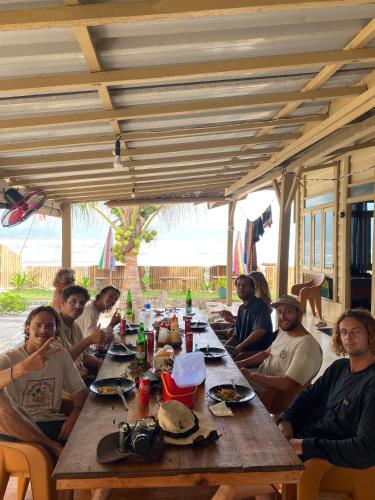 a group of people sitting around a wooden table at Jenny's Bamboo Surf Camp in Karbang