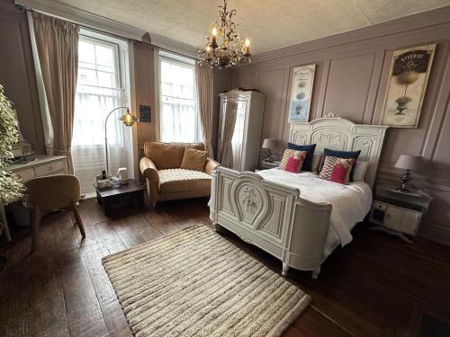 a bedroom with a bed and a chair and a chandelier at The Mansion House Hotel in Holbeach