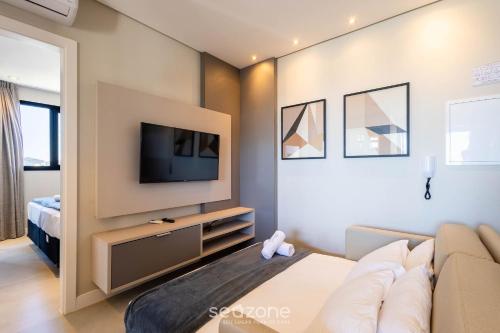 a living room with a couch and a tv at MHF II - Apts Variados em Prédio com Vista para o Mar em Itapema in Itapema