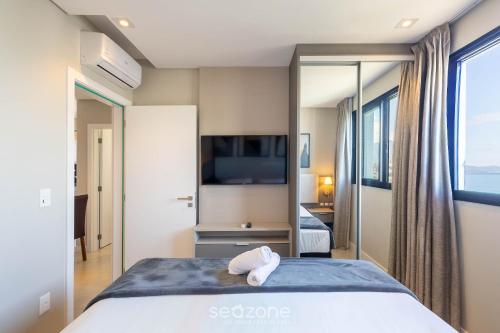 a hotel room with a bed and a tv at MHF II - Apts Variados em Prédio com Vista para o Mar em Itapema in Itapema