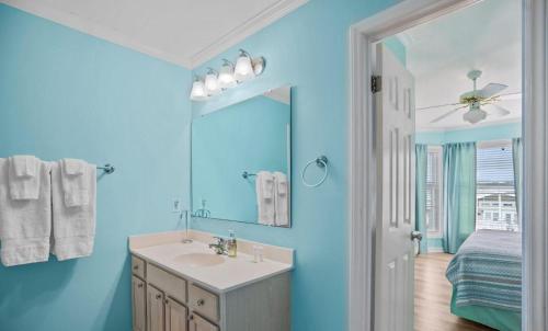 Un baño azul con lavabo y espejo. en Beach Dream, en Holden Beach