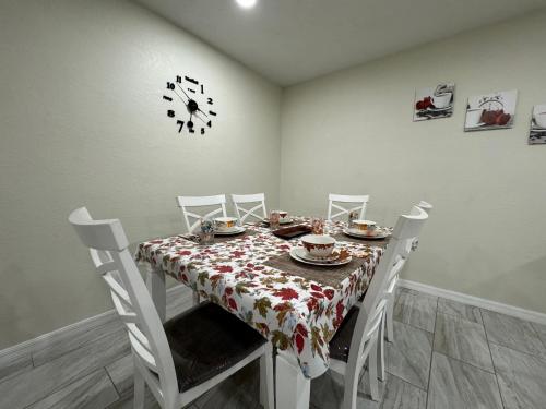 a dining room with a table and chairs and a clock at Sunshine Nest in Lehigh Acres