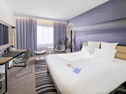 a hotel room with a large bed and a desk at Novotel Katowice Centrum in Katowice