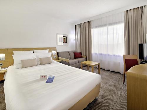 a hotel room with a large white bed and a couch at Novotel Katowice Centrum in Katowice