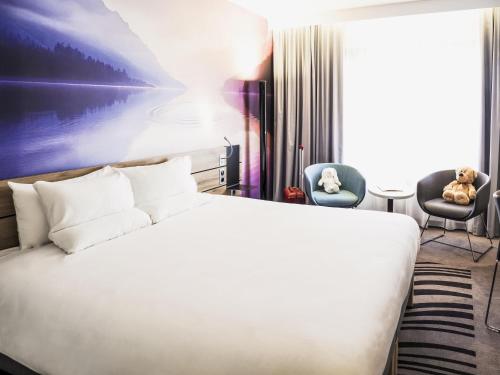 a bedroom with a white bed and two chairs at Novotel Katowice Centrum in Katowice