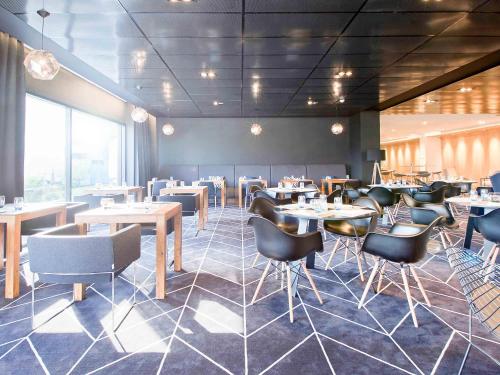 a restaurant with tables and chairs in a room at Novotel Katowice Centrum in Katowice