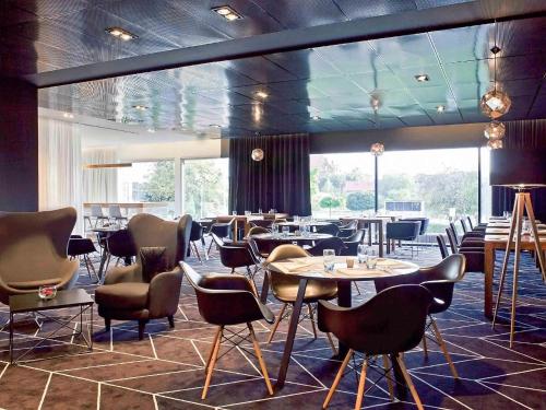 a restaurant with tables and chairs and a large window at Novotel Katowice Centrum in Katowice