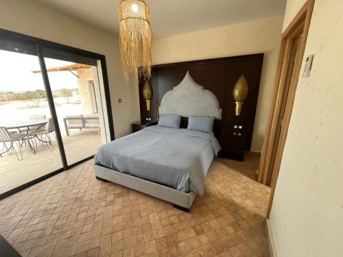 a bedroom with a bed and a balcony with a table at Dar'S in Moulay Douraïne