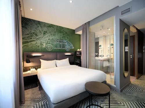 a bedroom with a large white bed and a bathroom at Mercure Warszawa Grand in Warsaw