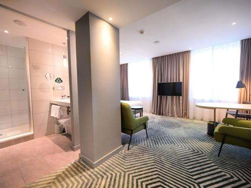 a hotel room with a table and chairs and a living room at Mercure Warszawa Grand in Warsaw