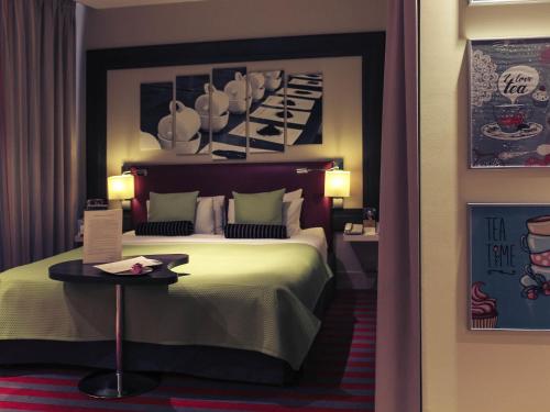 a hotel room with a bed and a table at Mercure Warszawa Grand in Warsaw