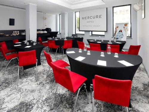 a conference room with tables and red chairs at Mercure Warszawa Grand in Warsaw