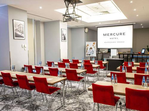 a conference room with tables and red chairs at Mercure Warszawa Grand in Warsaw