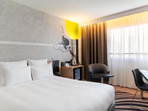 a hotel room with a white bed and a desk at Novotel Warszawa Centrum in Warsaw