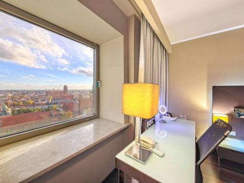 a room with a window and a desk with a lamp at Mercure Gdańsk Stare Miasto in Gdańsk