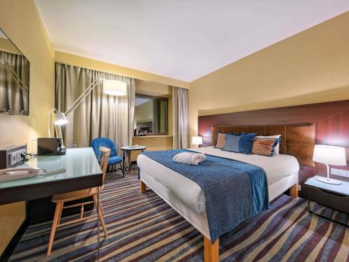 a hotel room with a bed and a desk at Mercure Gdańsk Stare Miasto in Gdańsk