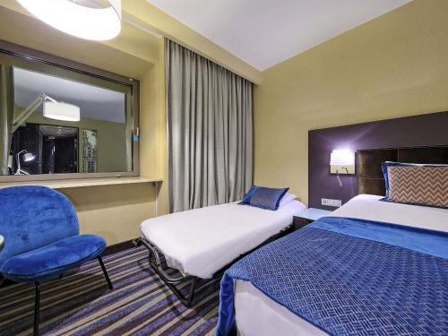 a hotel room with two beds and a chair at Mercure Gdańsk Stare Miasto in Gdańsk