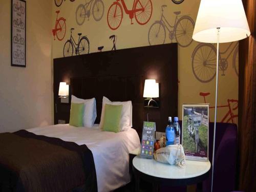 a hotel room with a bed and a table with a lamp at Mercure Gdańsk Stare Miasto in Gdańsk