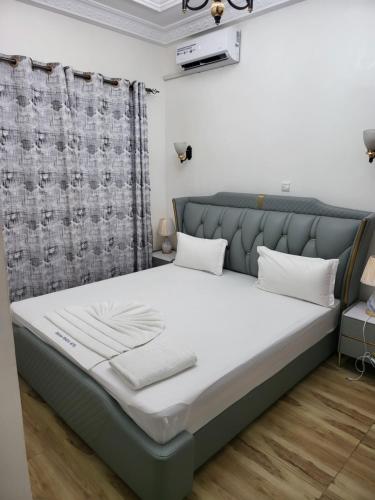 a bedroom with a large bed with a gray headboard at Complexe Ebouna-Pendza in Pointe-Noire