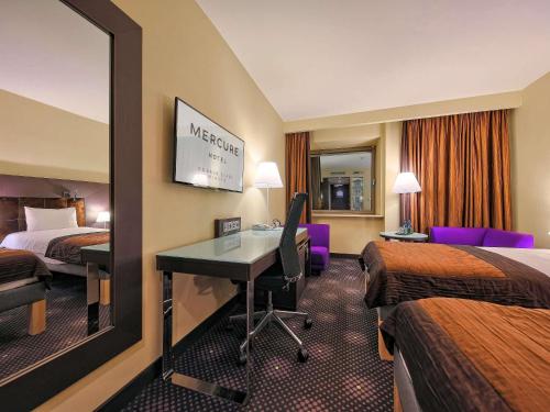 a hotel room with a desk and two beds at Mercure Gdańsk Stare Miasto in Gdańsk