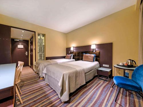 a hotel room with two beds and a blue chair at Mercure Gdańsk Stare Miasto in Gdańsk