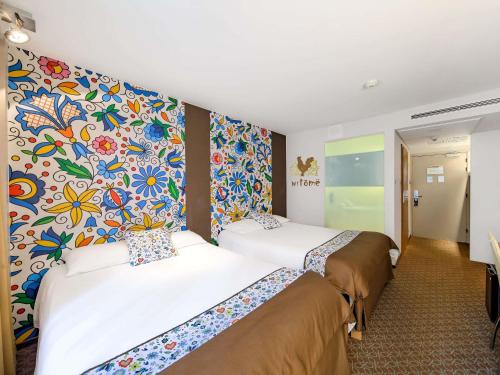 a hotel room with two beds and a colorful wall at Mercure Gdańsk Posejdon in Gdańsk