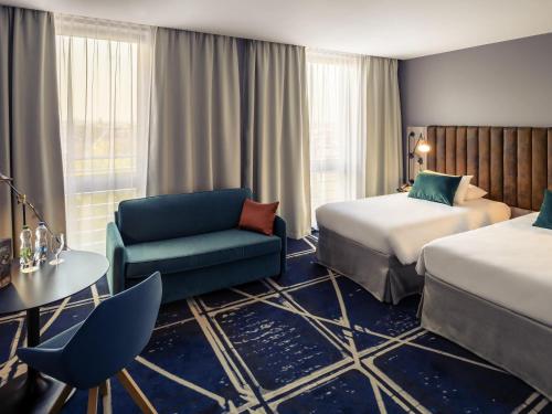 une chambre d'hôtel avec deux lits et une chaise dans l'établissement Hotel Mercure Poznań Centrum, à Poznań