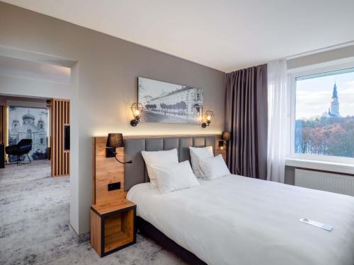 a hotel room with a large bed and a window at Mercure Czestochowa Centrum in Częstochowa