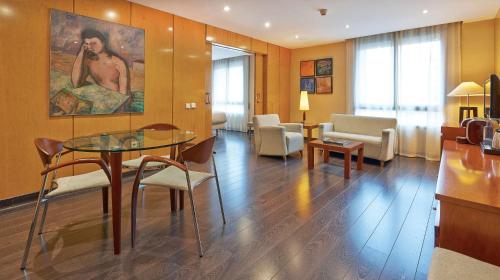 a living room with a glass table and chairs at NH Lleida Pirineos in Lleida