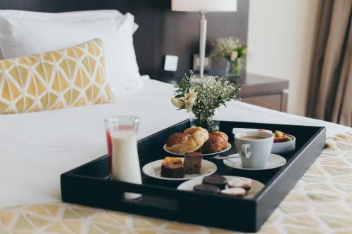 a tray of food on a bed with coffee and pastries at Wyndham Nordelta Tigre - Buenos Aires in Tigre