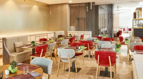 a restaurant with wooden tables and chairs and red chairs at NH Collection Marseille in Marseille